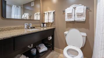 Un baño con lavamanos, espejo, inodoro y toallas.