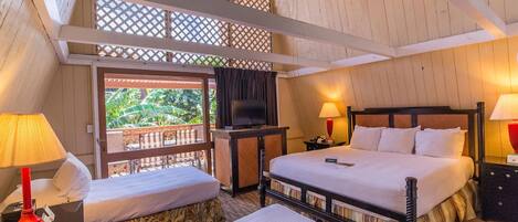 A hotel room with two beds, a TV, and a balcony with a view of greenery.