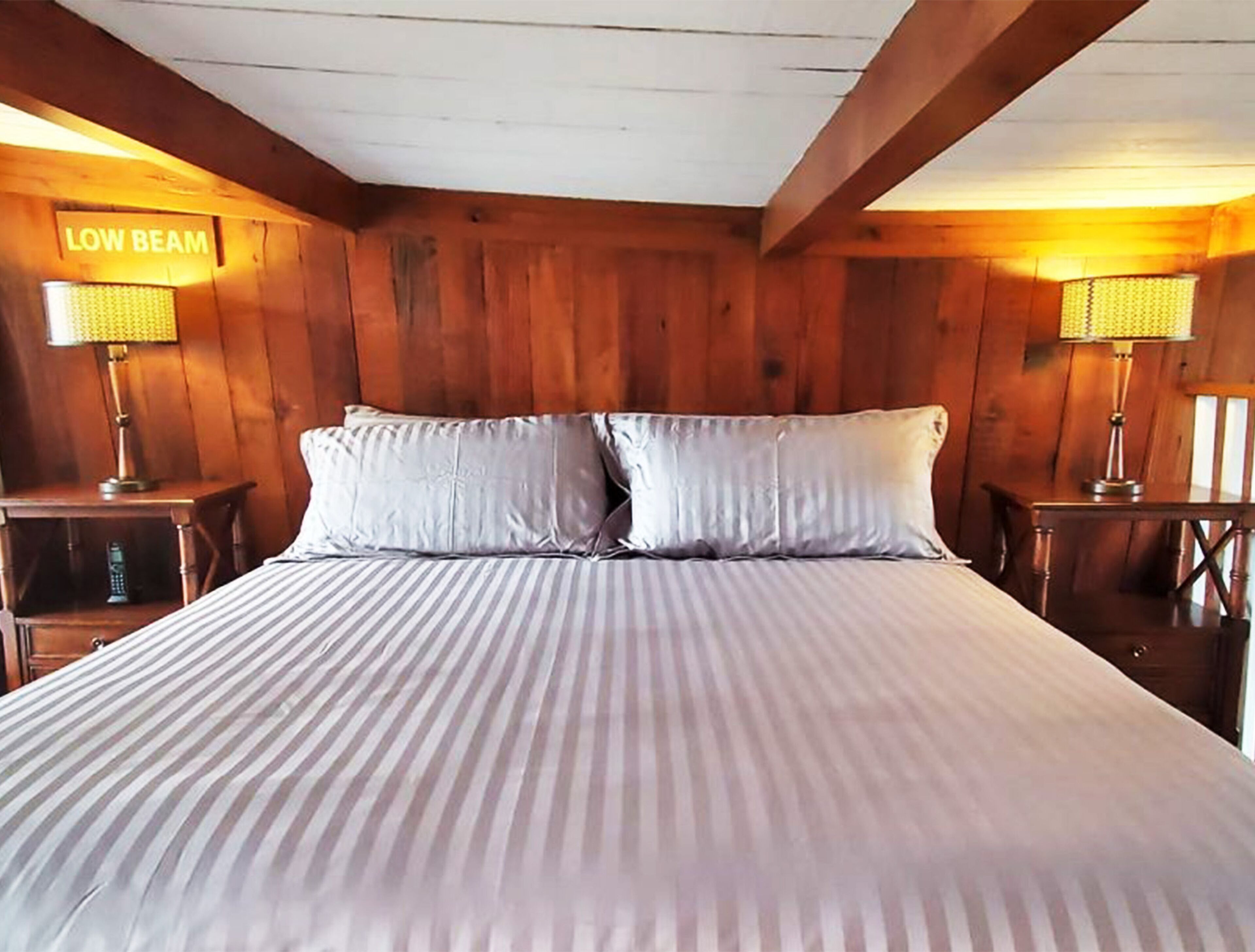 A room with a bed, two nightstands, and a sign that reads "LOW BEAM".