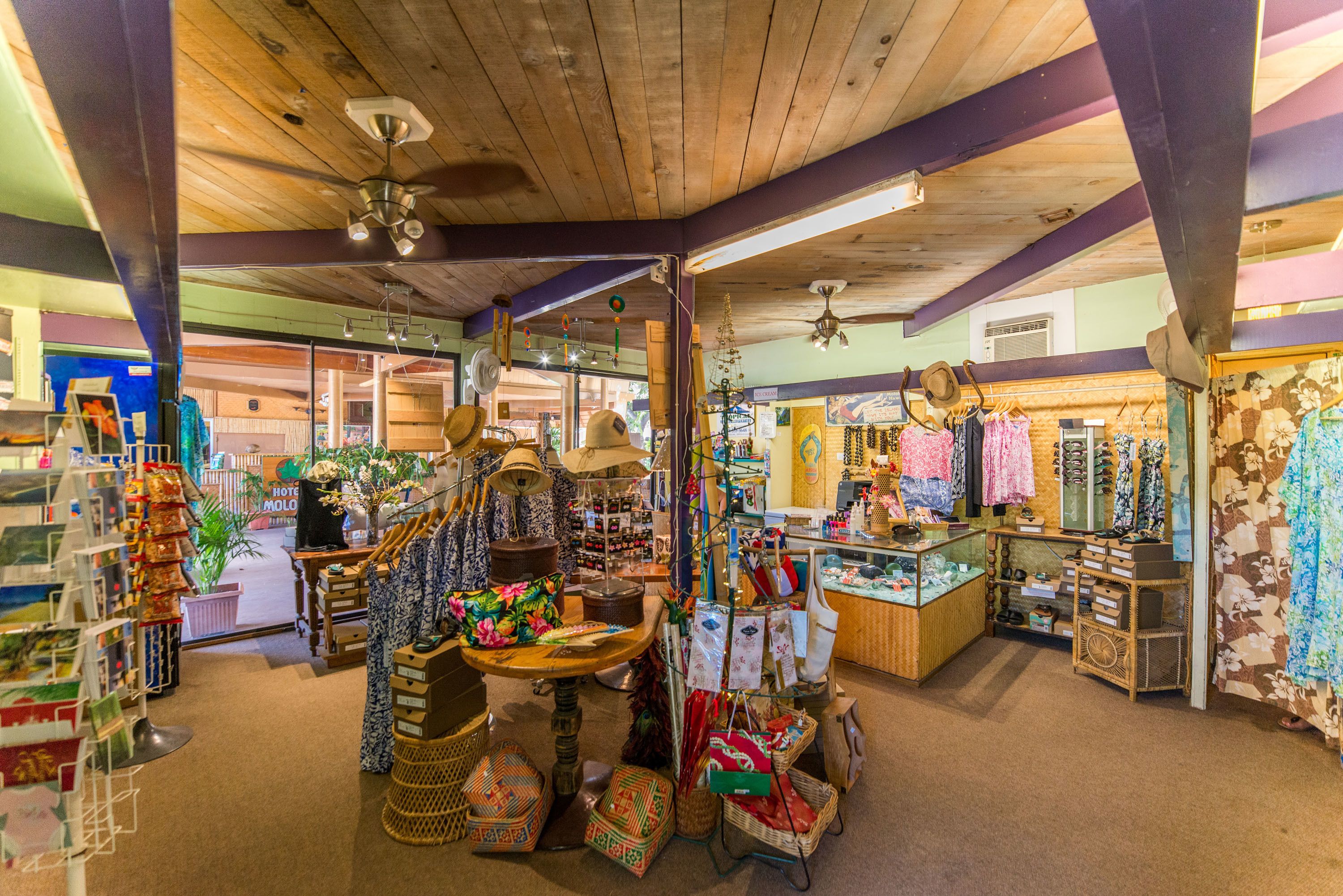 A boutique hotel interior with wooden beams, a central table with baskets, and various items on display including hats and bags.