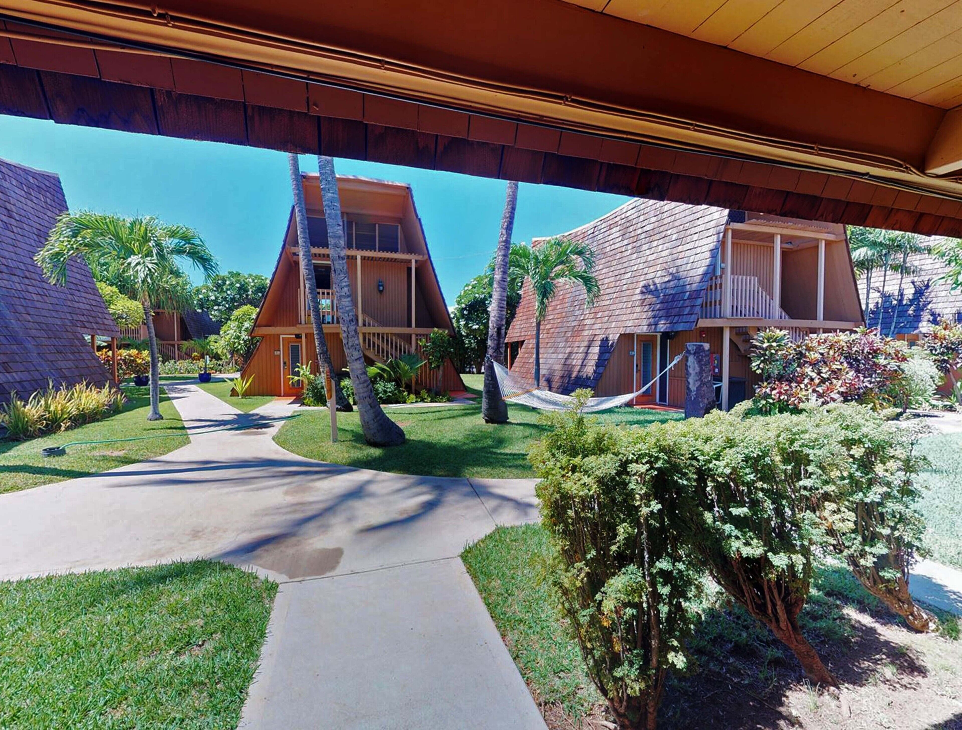 A resort with two bungalow-style buildings, a central pathway, and surrounding tropical vegetation.