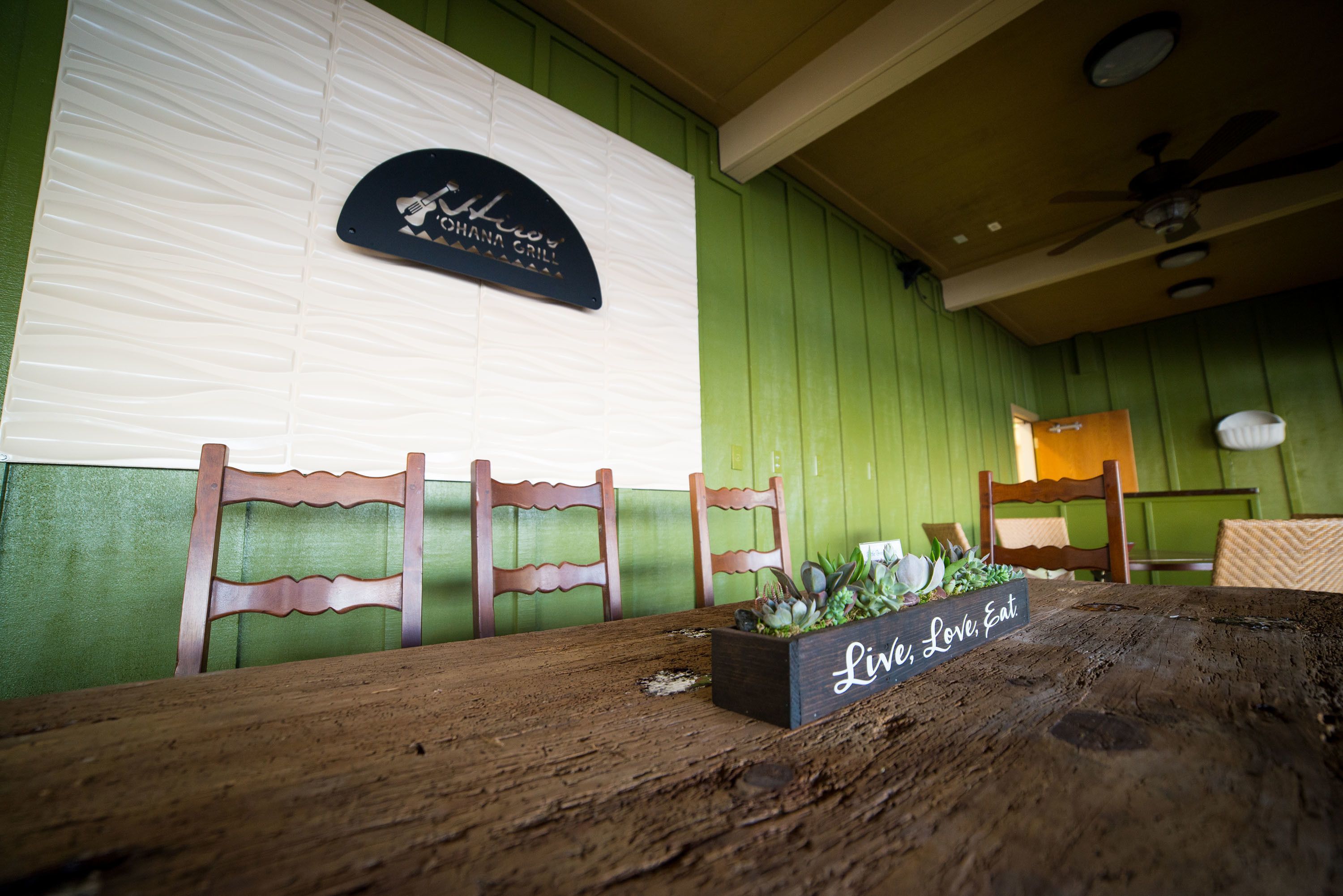 Una mesa de madera con un cajón para plantas con la etiqueta "Life, Love, Eat" y un cartel encima.