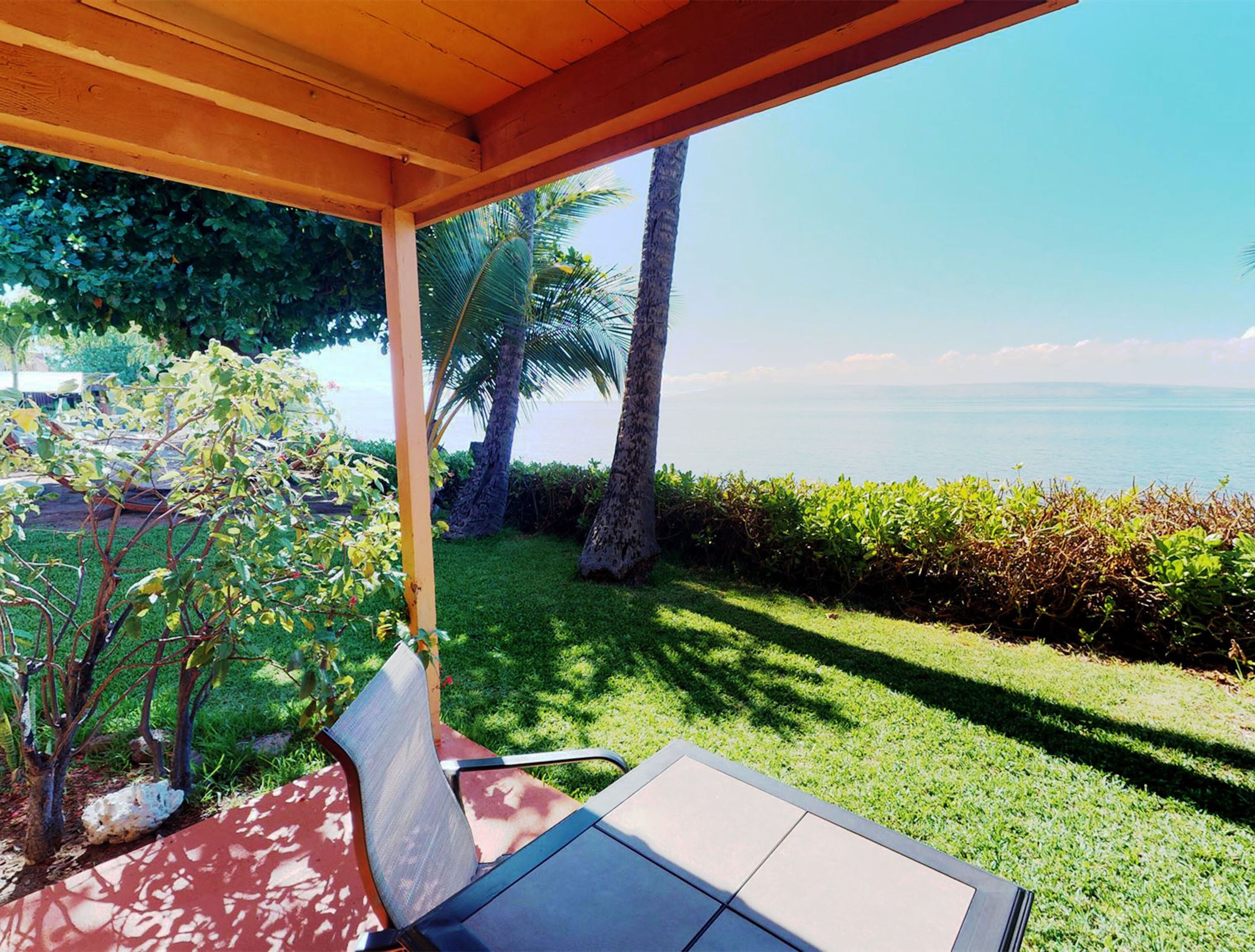 A covered outdoor seating area with a view of the sea.