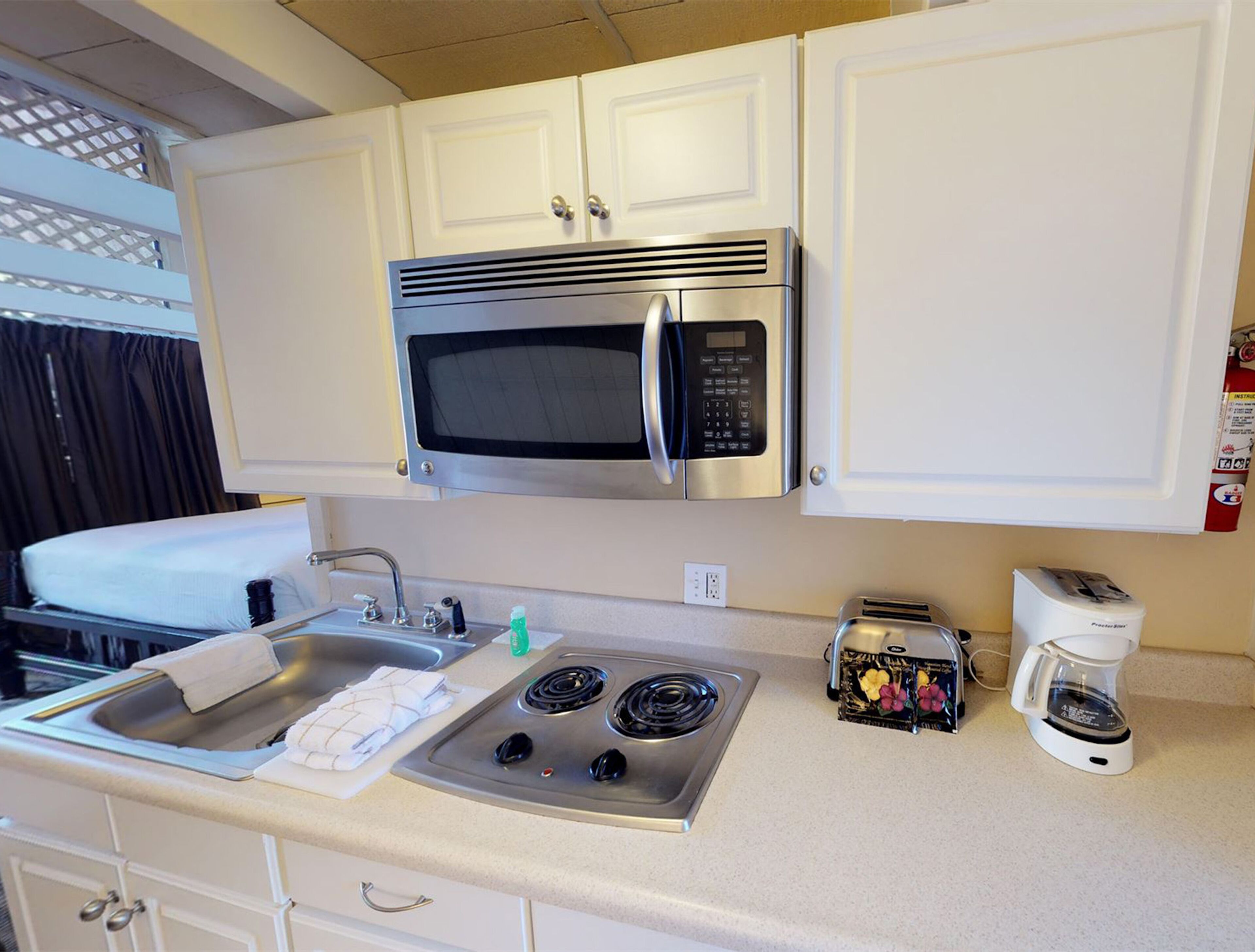 Una kitchenette compacta con microondas, estufa, fregadero y tostadora.