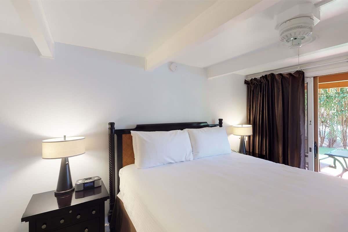 Ein Hotelzimmer mit einem Bett, zwei Nachttischlampen, einem Nachttisch und einer Deckenleuchte.