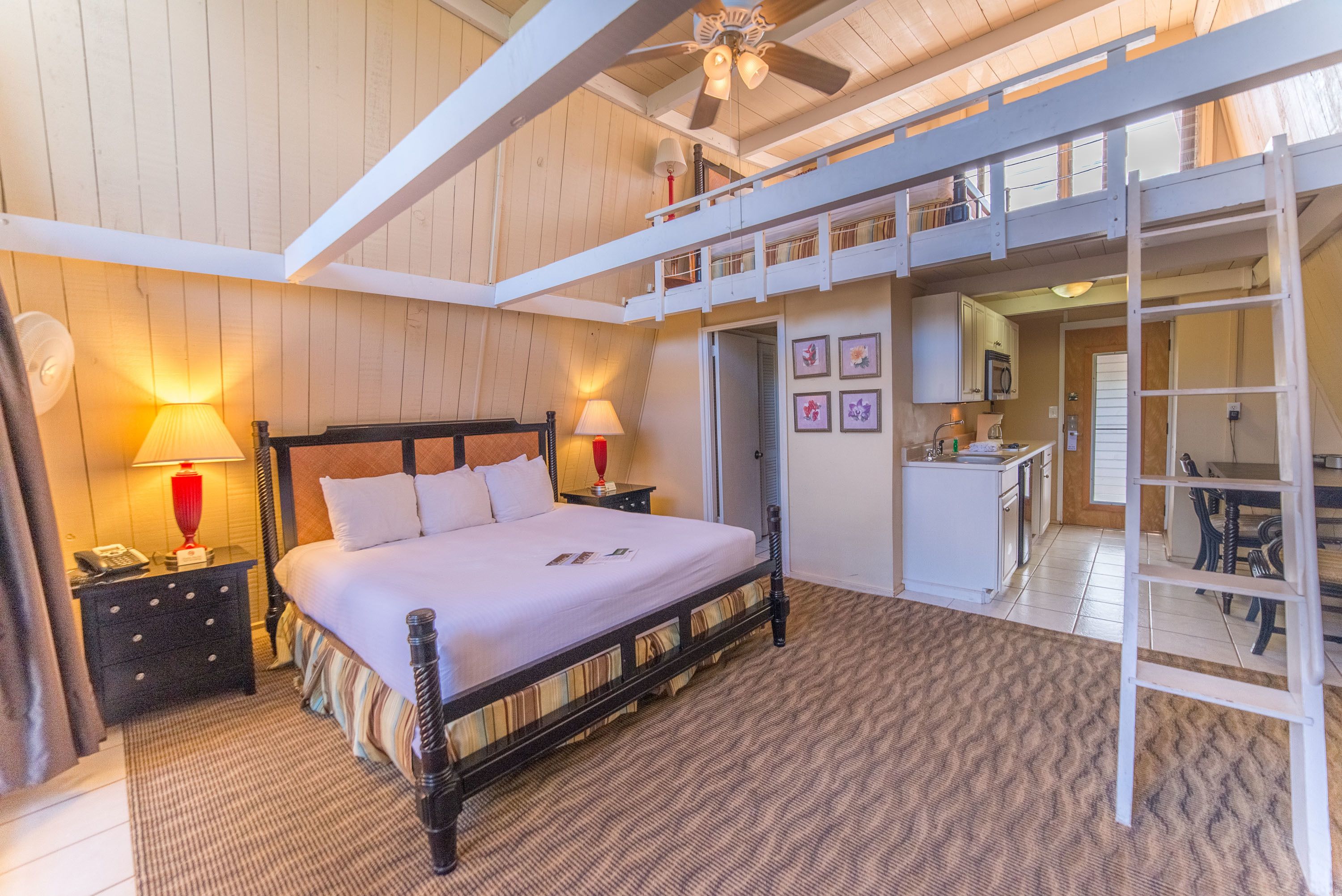 Une chambre spacieuse avec un grand lit, un plafond en bois et un balcon.