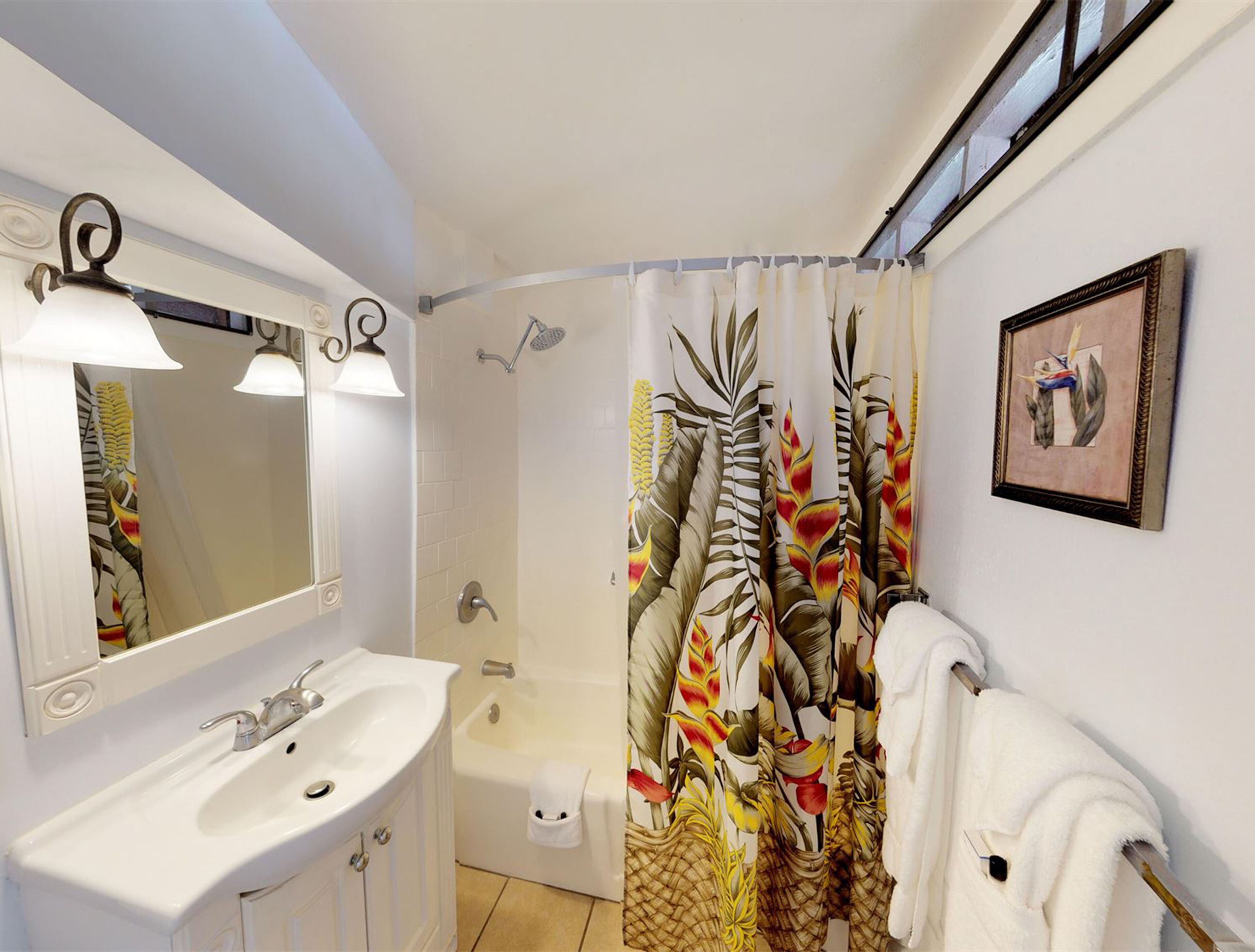 A bathroom with a white sink, a mirror, a shower, and a towel rack.