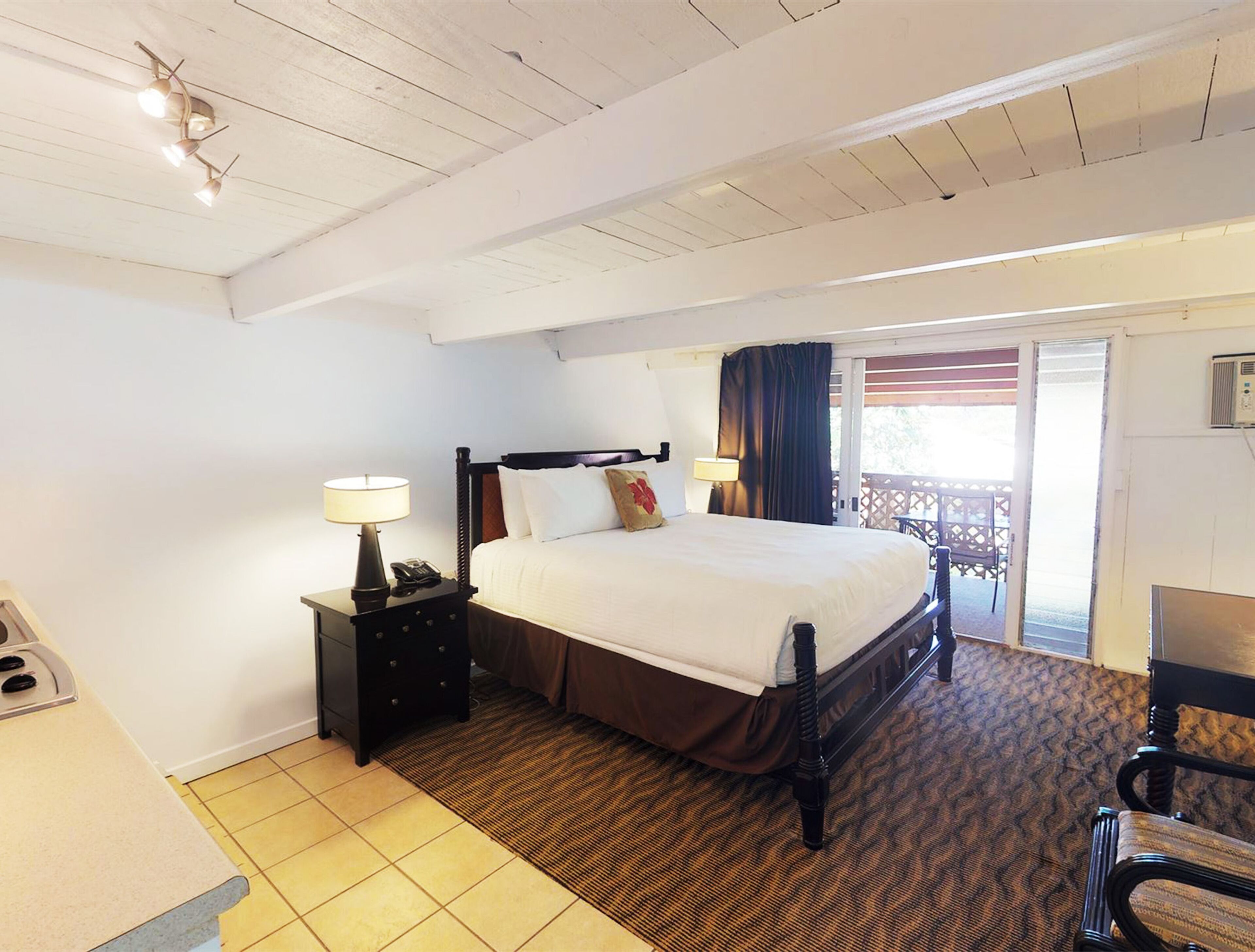 Une chambre d’hôtel avec un lit, une table de chevet, une lampe, une chaise et une vue sur l’extérieur.