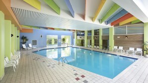 An indoor swimming pool with clear blue water, surrounded by white lounge chairs and a tiled floor. - Heidel House Resort & Spa (Green Lake)