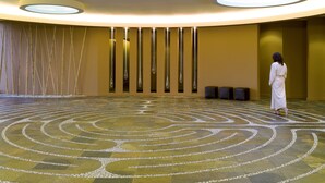 A spacious lobby with a circular floor design, a woman walking, and a modern ceiling with recessed lighting. - Heidel House Resort & Spa (Green Lake)
