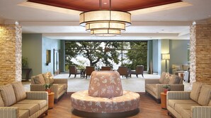 A spacious lobby with a central round seating area, wooden flooring, and a large window offering a view of trees. - Heidel House Resort & Spa (Green Lake)