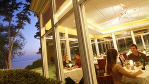 An outdoor dining area with tables and chairs, large windows, and a view of the sky. - Heidel House Resort & Spa (Green Lake)