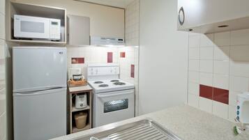 A compact kitchen with a microwave, refrigerator, stove, oven, and a sink.