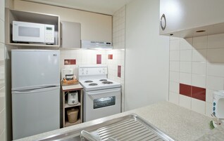 Une cuisine compacte équipée d’un four à micro-ondes, d’un réfrigérateur, d’une cuisinière, d’un four et d’un évier.