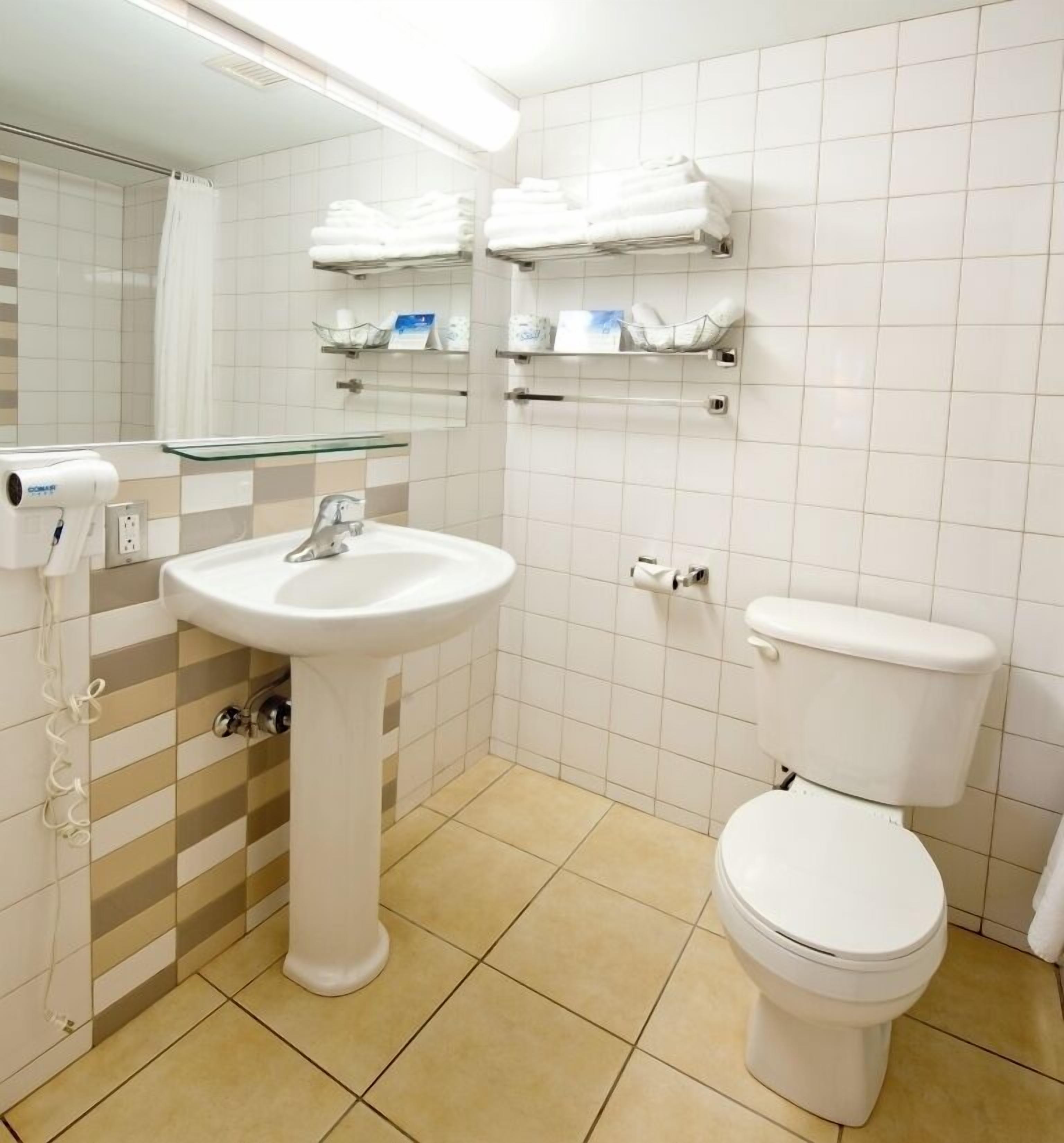 Une salle de bain équipée d’un lavabo, de toilettes et de porte-serviettes.