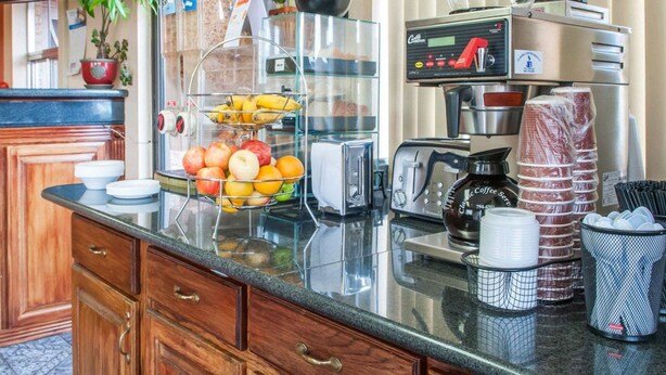 A kitchen counter with a fruit bowl, a coffee machine, and various kitchen appliances. - Econo Lodge Hobbs (Hobbs)