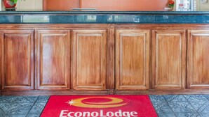 A reception area with a wooden reception desk, a clock, and a sign for EconoLodge by Choice Hotels. - Econo Lodge Hobbs (Hobbs)
