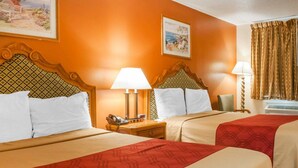 A hotel room with two beds, each with a headboard, bedside tables, lamps, and a telephone. - Econo Lodge Hobbs (Hobbs)