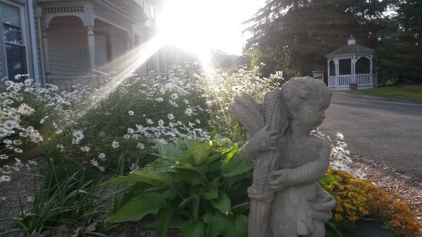 A garden with a stone angel statue, white flowers, and a gazebo. - Albergo Allegria Hotel (Windham)