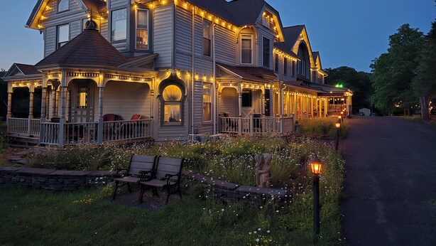 A large, two-story house with multiple porches and string lights. - Albergo Allegria Hotel (Windham)