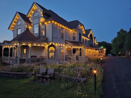 A large, two-story house with multiple porches and string lights.