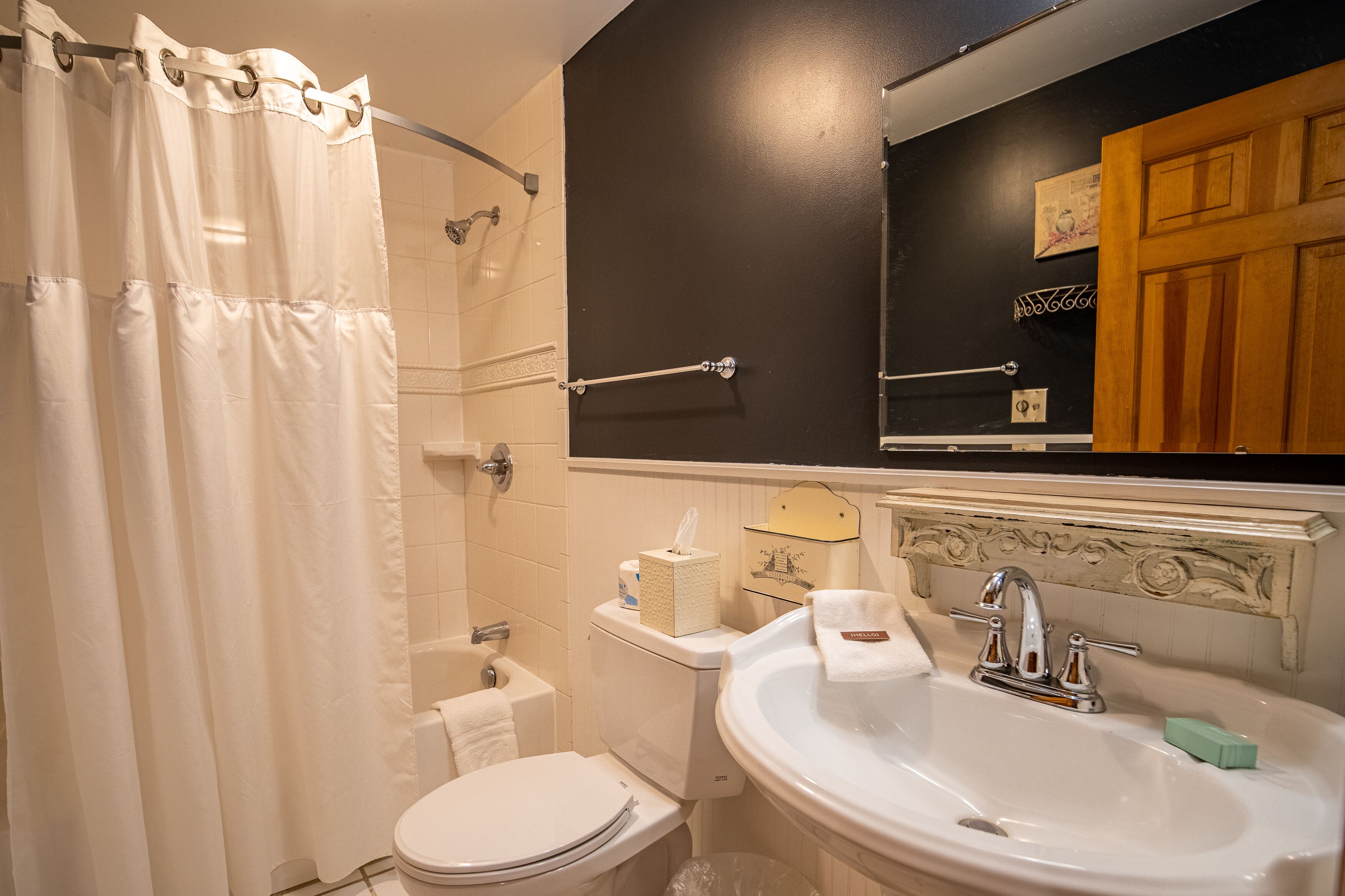 A bathroom with a shower curtain, toilet, sink, and a mirror above the sink.