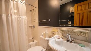 A bathroom with a shower curtain, toilet, sink, and a mirror above the sink.