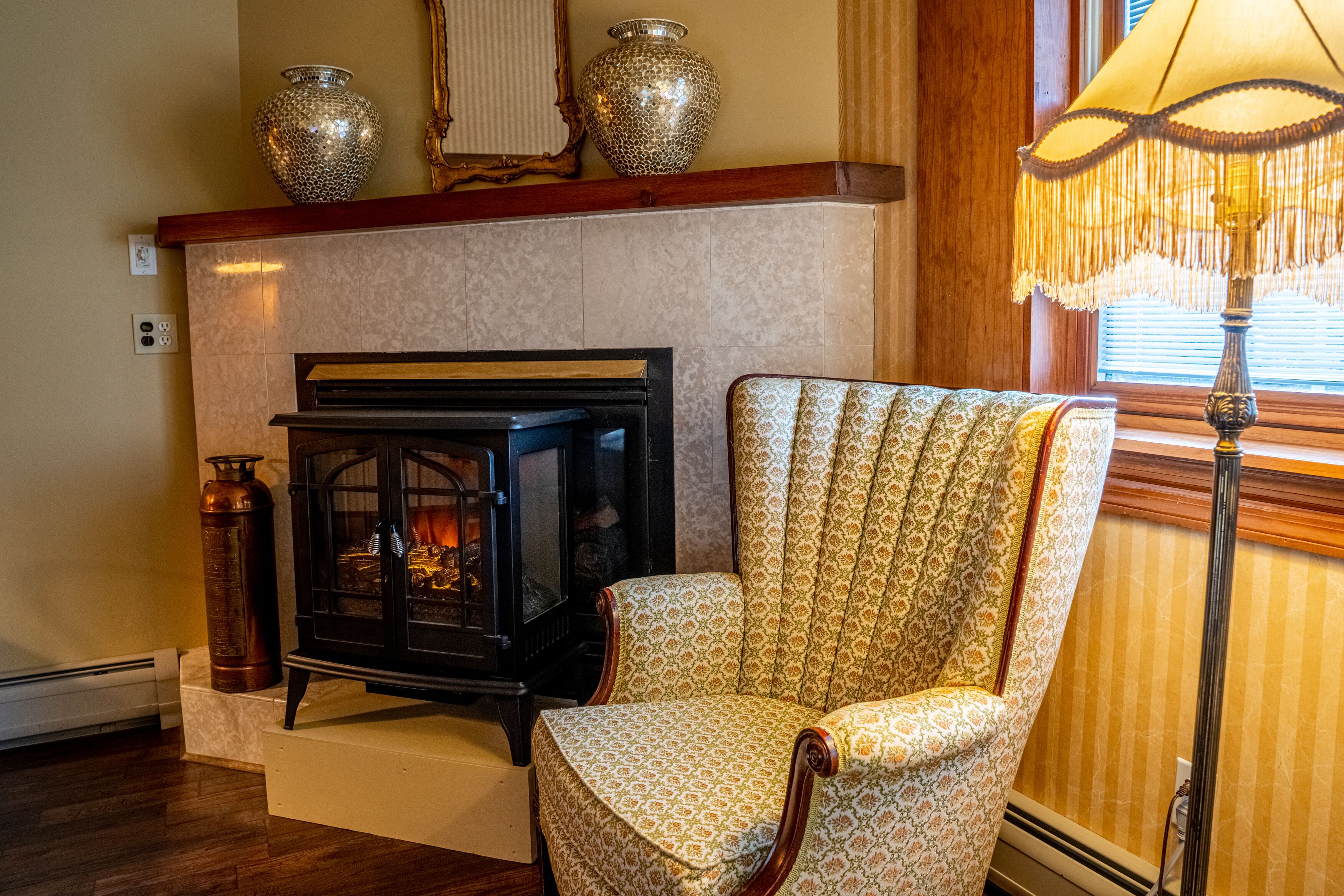 A cozy room with a fireplace, a patterned armchair, and decorative vases.