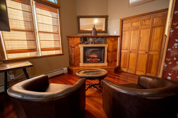 A cozy living room with a fireplace, leather chairs, and wooden flooring. - Albergo Allegria Hotel (Windham)