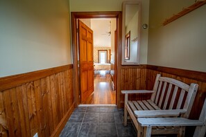 A hallway with wooden paneling, a bench, and a door leading to a bedroom. - Albergo Allegria Hotel (Windham)