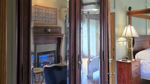 A room with a wooden wardrobe, a bed, a nightstand, a lamp, and a fireplace. - Albergo Allegria Hotel (Windham)