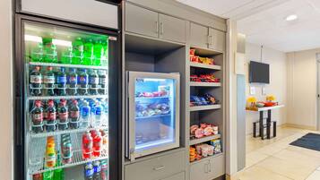 A vending machine stocked with various beverages and a refrigerator with snacks.