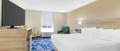 A hotel room with a large bed, a flat-screen TV, a desk, a chair, and a window with a view.