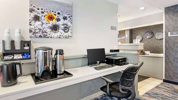 Una recepción con una estación de café, una computadora y una silla.