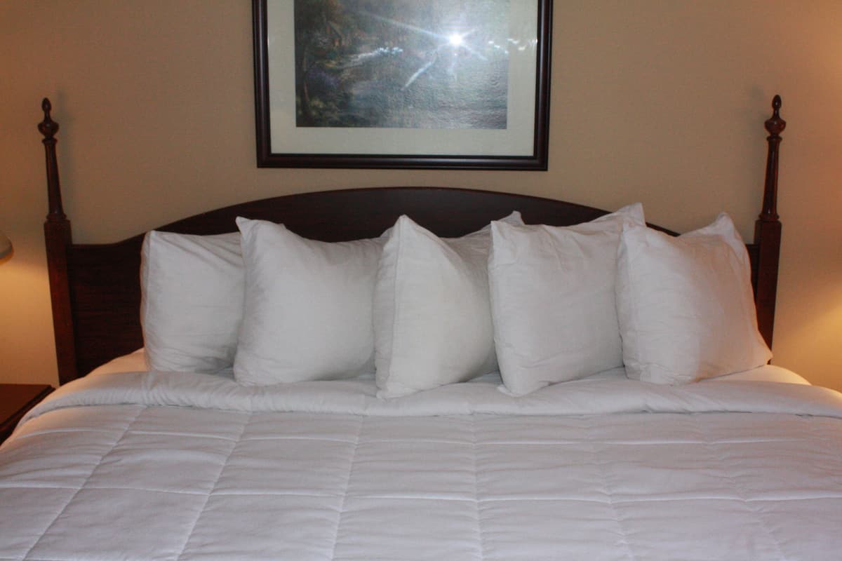 A neatly made bed with a dark wooden headboard and white bedding.