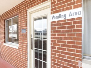 A brick building with a white door and a sign indicating a vending area. - Mansion View Inn and Suite (Springfield)