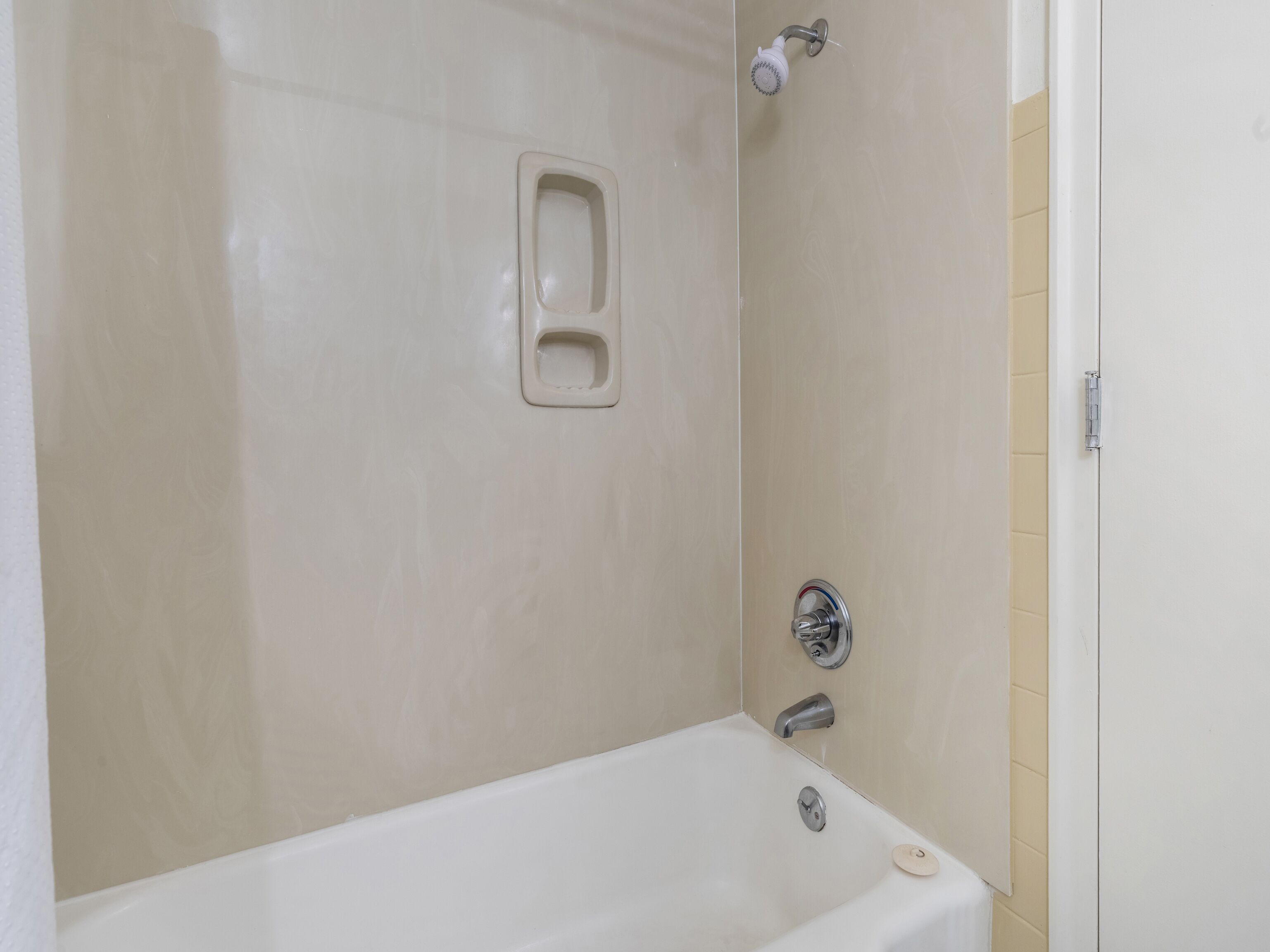 A bathroom with a bathtub, a showerhead, and a toilet.