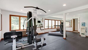 Ett gym med träningsutrustning, stora fönster och en vattenautomat.