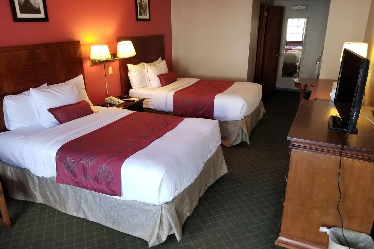 Quarto de hotel com duas camas, uma escrivaninha, televisão e telefone.