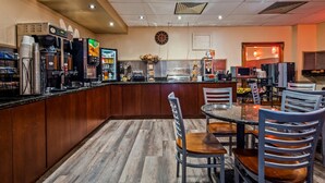Een restaurant met een bar, houten kasten en een klok aan de muur.
