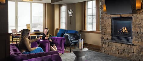 A room with a fireplace, purple seating, and a stone wall.