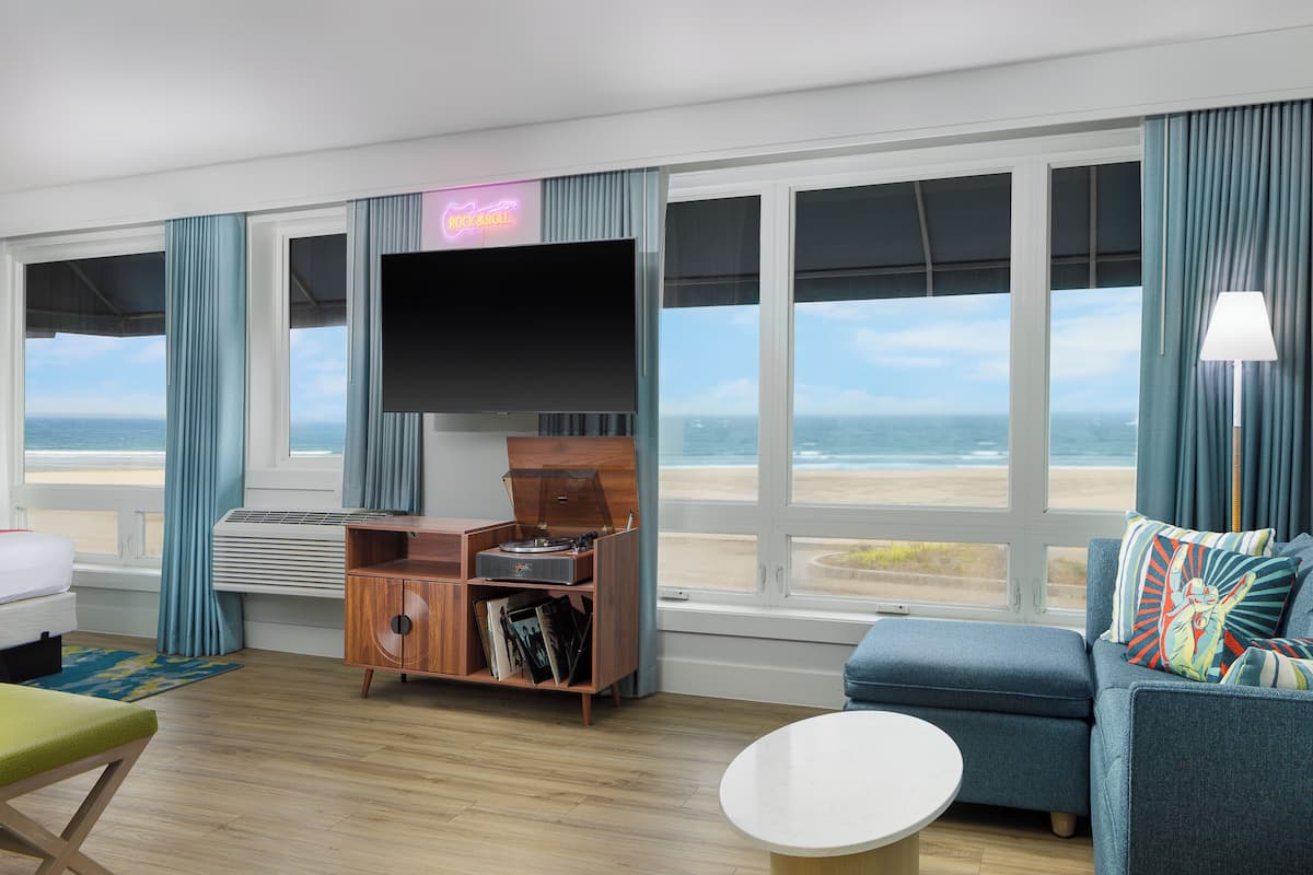 Ein Zimmer mit einem großen Fernseher, einer Holzeinrichtung, einer Couch und Blick auf den Strand.