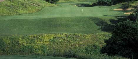 A golf course with a clubhouse, a tower, and a well-maintained landscape.