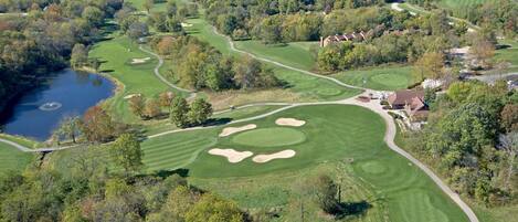 A golf course with a lake, sand bunkers, and a clubhouse.