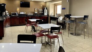 Un café propre et bien éclairé, doté d’un téléviseur à écran plat, d’un comptoir de buffet et d’un espace avec des tables et des chaises.