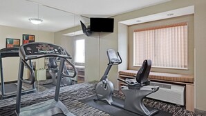 Une salle de sport équipée de tapis de course, d’un vélo elliptique et d’un banc de musculation.