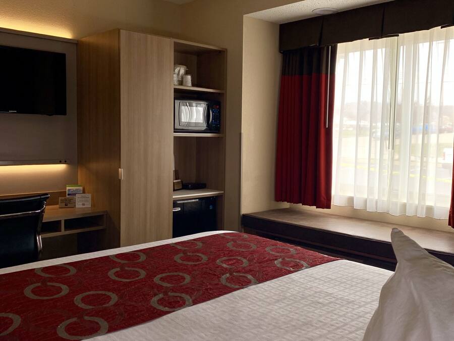 A hotel room with a bed, a desk, a microwave, and a TV.