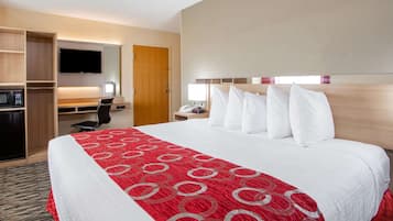 Habitación de hotel con una cama grande, un escritorio con computadora, televisión y minibar.