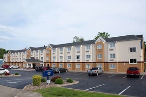 Un hôtel à plusieurs étages doté d’un parking, de plusieurs véhicules et d’une enseigne indiquant qu’il s’agit d’un hôtel Marriott.