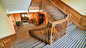 A grand staircase with a herringbone patterned carpet and wooden balusters.